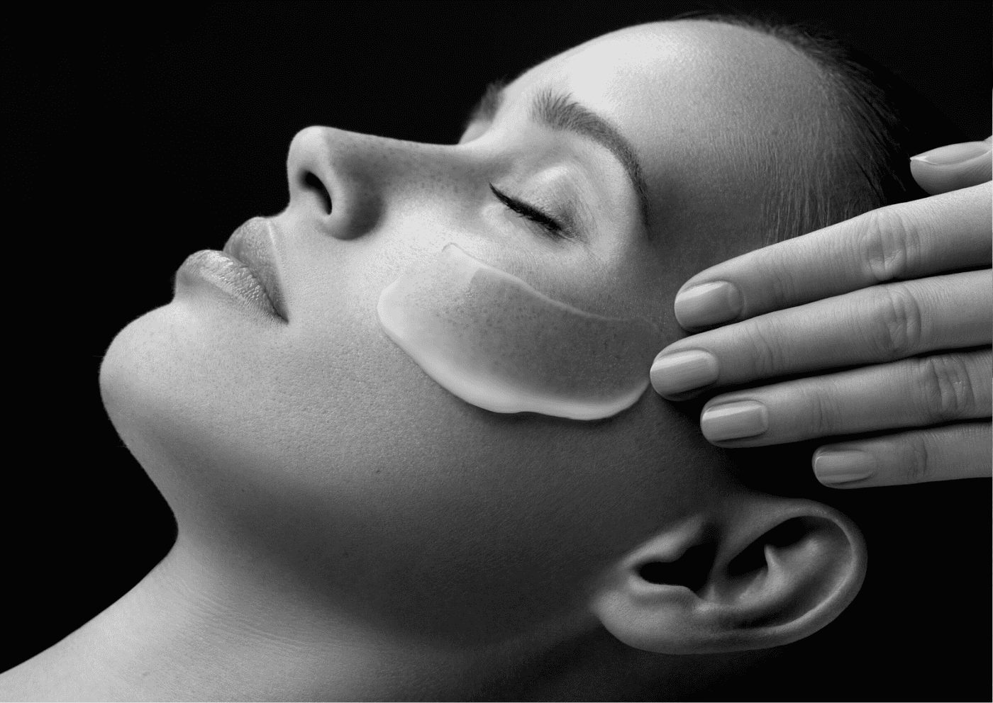Woman receiving facial treatment with eye pad in a spa setting.